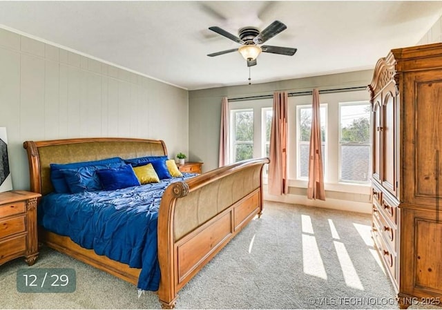 bedroom with a ceiling fan, ornamental molding, and light carpet