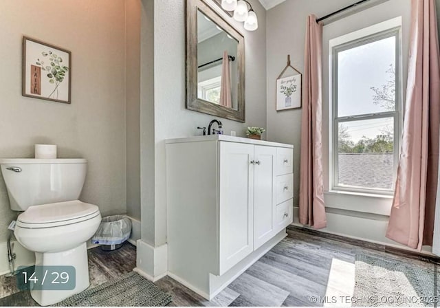 bathroom with wood finished floors, a healthy amount of sunlight, and toilet