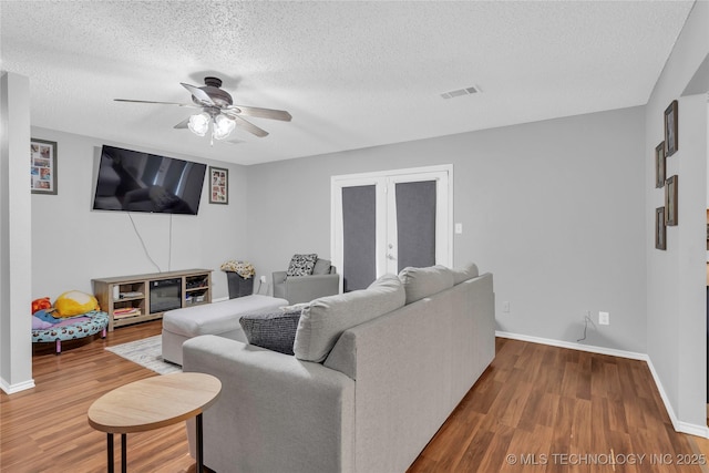 living room featuring baseboards, visible vents, wood finished floors, and a ceiling fan