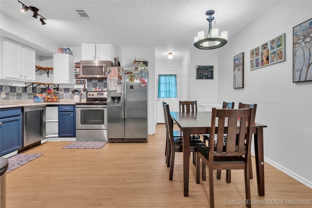 kitchen with open shelves, white cabinets, visible vents, stainless steel appliances, and blue cabinetry