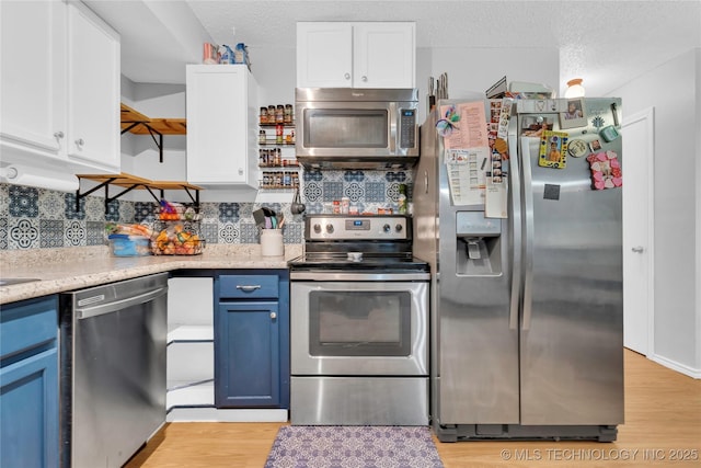 kitchen featuring open shelves, white cabinets, appliances with stainless steel finishes, blue cabinets, and backsplash