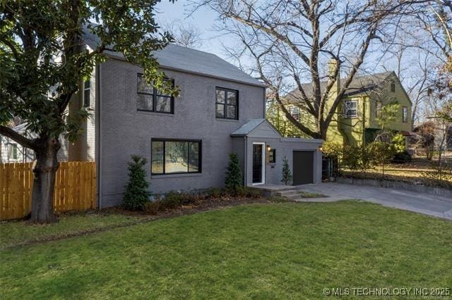 view of front of home with an attached garage, a front lawn, fence, and concrete driveway