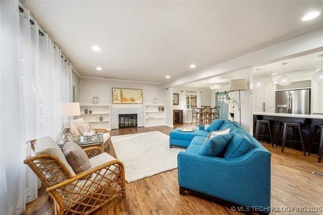 living area featuring a glass covered fireplace, recessed lighting, and wood finished floors