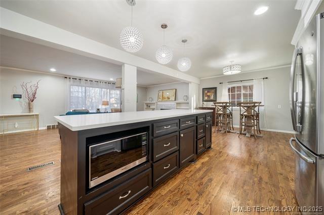 kitchen featuring light countertops, hanging light fixtures, appliances with stainless steel finishes, and wood finished floors