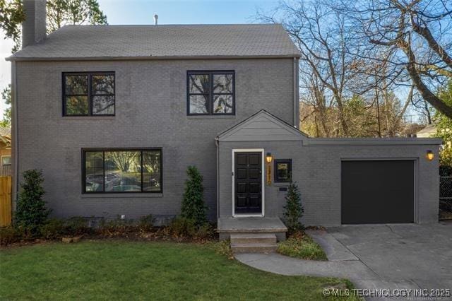 colonial-style house with fence, an attached garage, a front yard, a chimney, and driveway