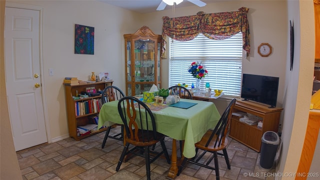 dining space with stone finish flooring, a ceiling fan, and baseboards