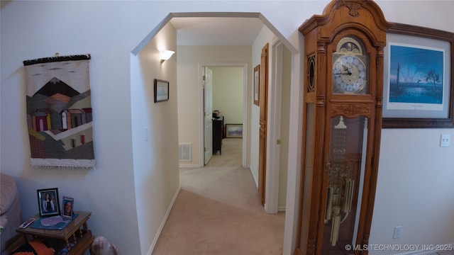 hall featuring arched walkways, visible vents, and light carpet