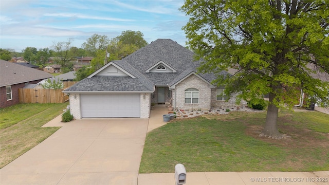 view of front of home with a front yard, brick siding, roof with shingles, concrete driveway, and fence