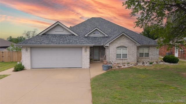 ranch-style house with concrete driveway, a shingled roof, brick siding, a front lawn, and a garage