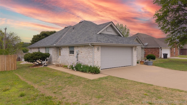 view of front of house with a yard, brick siding, a shingled roof, driveway, and an attached garage
