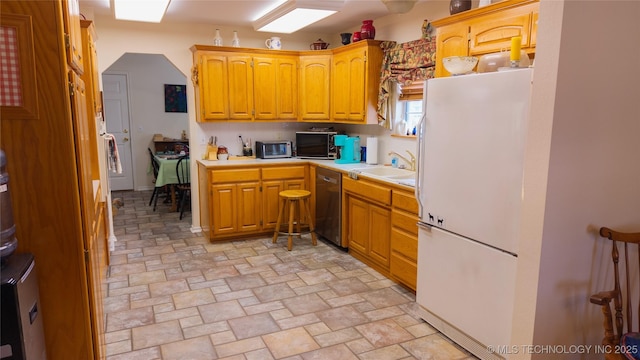 kitchen with appliances with stainless steel finishes, stone finish floor, light countertops, and a sink