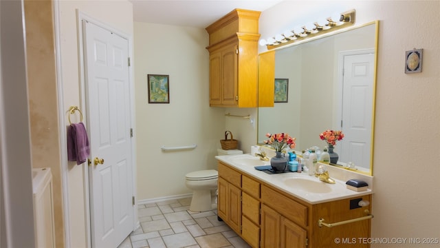 bathroom with double vanity, toilet, baseboards, and a sink