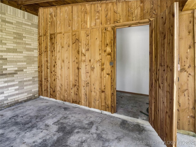 unfurnished room featuring wooden walls and baseboards