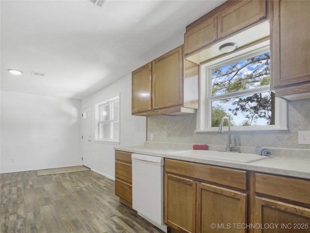kitchen featuring decorative backsplash, white dishwasher, wood finished floors, light countertops, and a sink