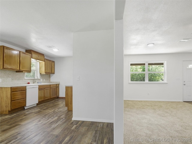 kitchen with brown cabinetry, dark wood finished floors, dishwasher, light countertops, and baseboards