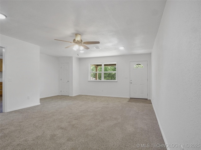 carpeted empty room featuring baseboards, a ceiling fan, and visible vents
