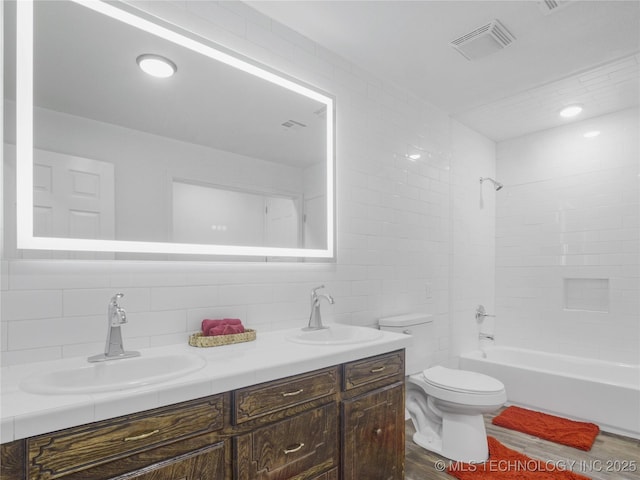 full bath with toilet, visible vents, a sink, and wood finished floors