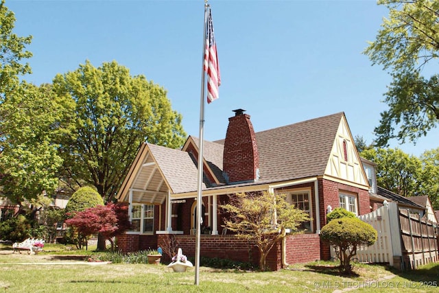 exterior space with roof with shingles, a chimney, a yard, and brick siding