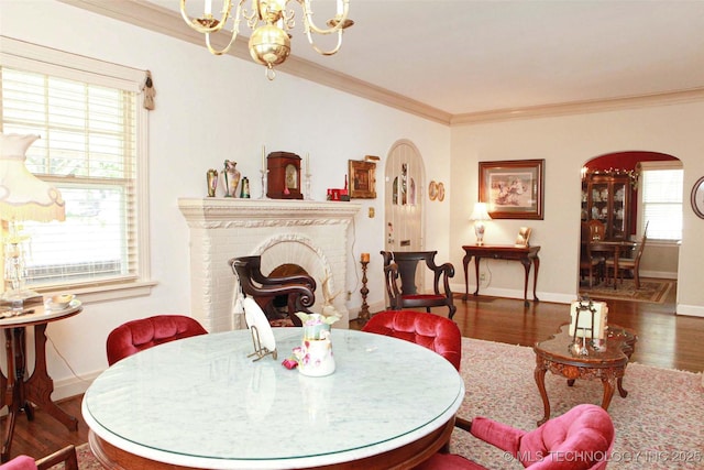 dining area with an inviting chandelier, baseboards, ornamental molding, arched walkways, and wood finished floors