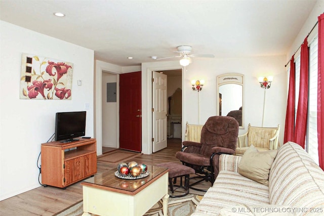 living area with recessed lighting, a ceiling fan, electric panel, and light wood-style flooring