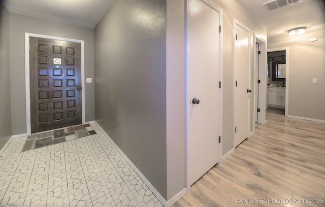 foyer featuring visible vents, light wood-style floors, and baseboards