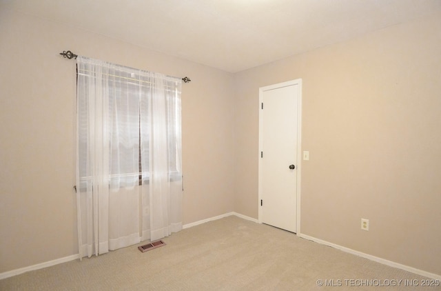 unfurnished room with visible vents, light colored carpet, and baseboards