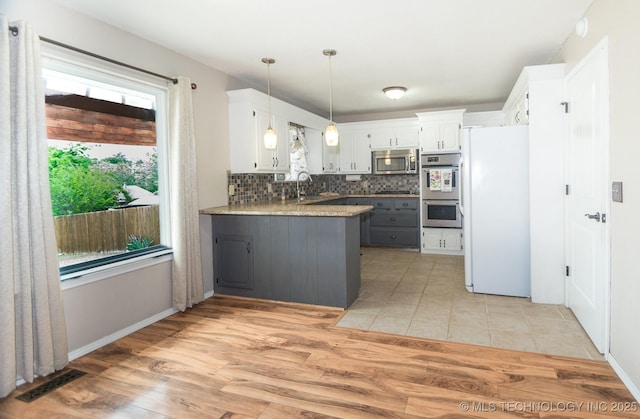 kitchen featuring light wood-style flooring, stainless steel appliances, backsplash, a sink, and visible vents