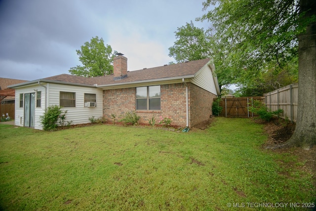 back of property with a chimney, a yard, brick siding, and a fenced backyard