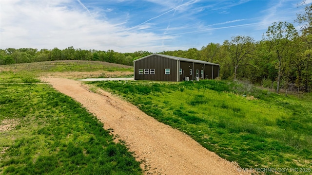 65365 E 155th Rd, Wyandotte, OK 74370 - view of yard with driveway, a pole building, a wooded view, and an outbuilding