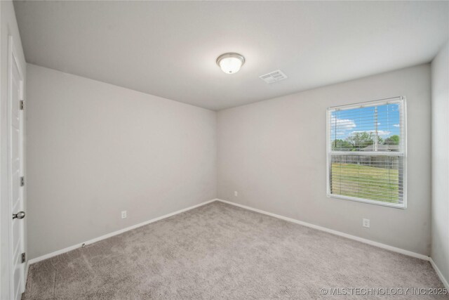 carpeted spare room featuring visible vents and baseboards