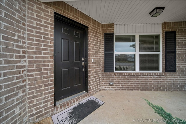 entrance to property with covered porch and brick siding
