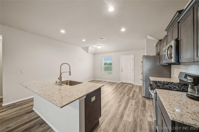 kitchen with light wood finished floors, a sink, stainless steel appliances, and baseboards