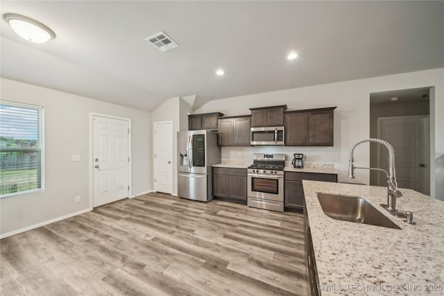 kitchen featuring a sink, visible vents, stainless steel appliances, dark brown cabinets, and light wood finished floors