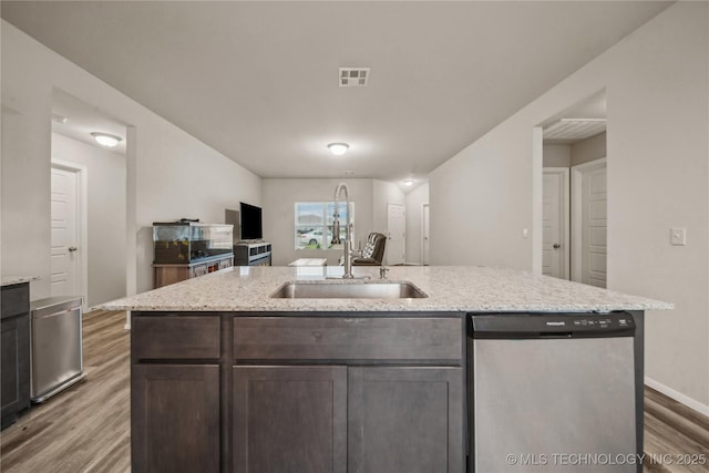 kitchen featuring light stone counters, stainless steel dishwasher, a sink, light wood-style floors, and dark brown cabinetry