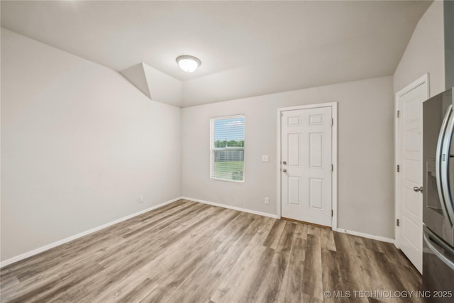 empty room with vaulted ceiling, wood finished floors, and baseboards