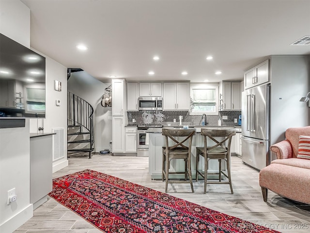 1805 W Easton St, Tulsa, OK 74127 - kitchen with stainless steel appliances, a kitchen bar, decorative backsplash, a center island, and recessed lighting