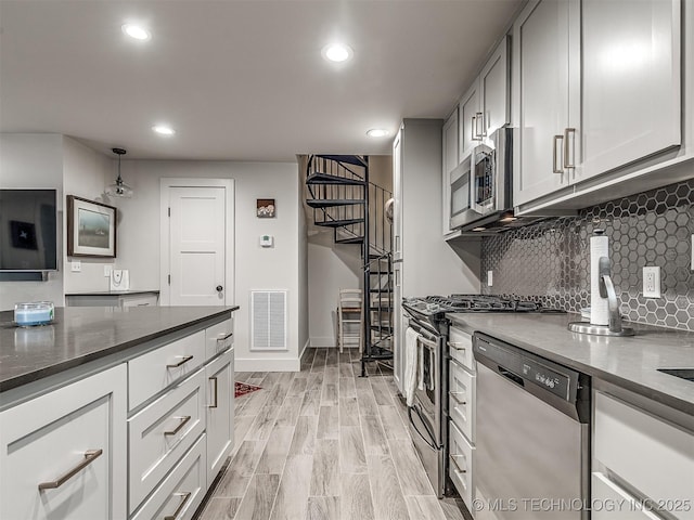 1805 W Easton St, Tulsa, OK 74127 - kitchen with appliances with stainless steel finishes, recessed lighting, decorative backsplash, dark stone countertops, and light wood-type flooring