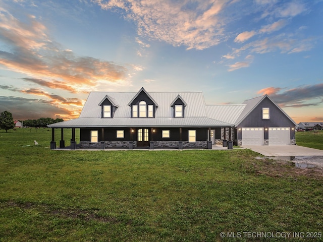 view of front facade featuring metal roof, a lawn, a garage, concrete driveway, and stone siding