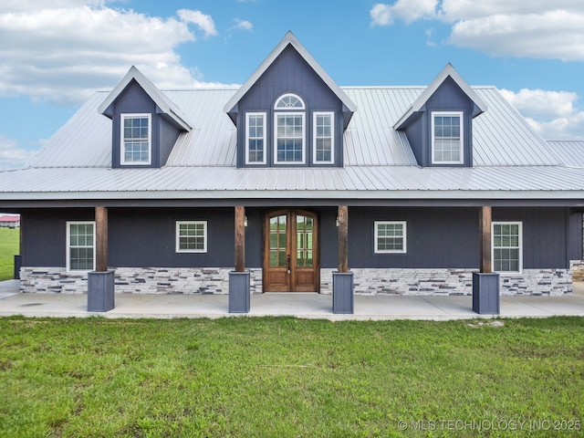 rear view of house with a lawn, stone siding, and metal roof