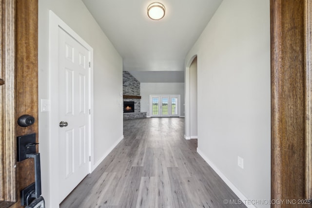 corridor with baseboards, arched walkways, and wood finished floors