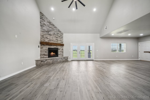 unfurnished living room featuring ceiling fan, visible vents, a fireplace, wood finished floors, and high vaulted ceiling