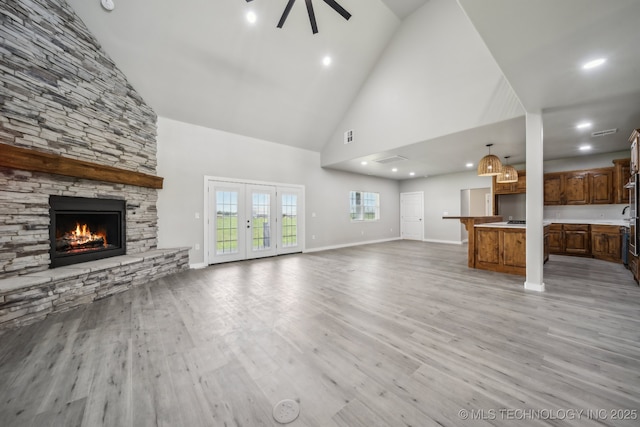 unfurnished living room with ceiling fan, a fireplace, high vaulted ceiling, light wood-style flooring, and baseboards