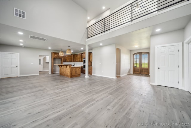 unfurnished living room featuring visible vents, baseboards, recessed lighting, light wood-type flooring, and arched walkways