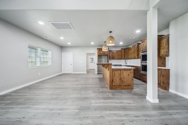 kitchen with recessed lighting, a center island, baseboards, light wood finished floors, and visible vents