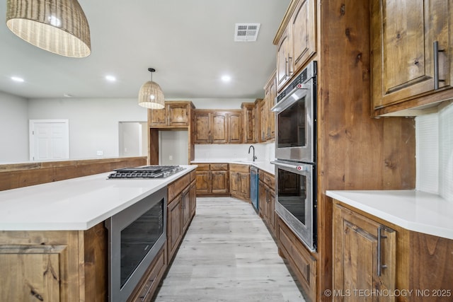 kitchen with light wood-style floors, visible vents, brown cabinets, and stainless steel appliances