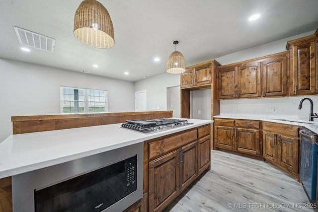 kitchen featuring a sink, light wood-type flooring, visible vents, light countertops, and appliances with stainless steel finishes