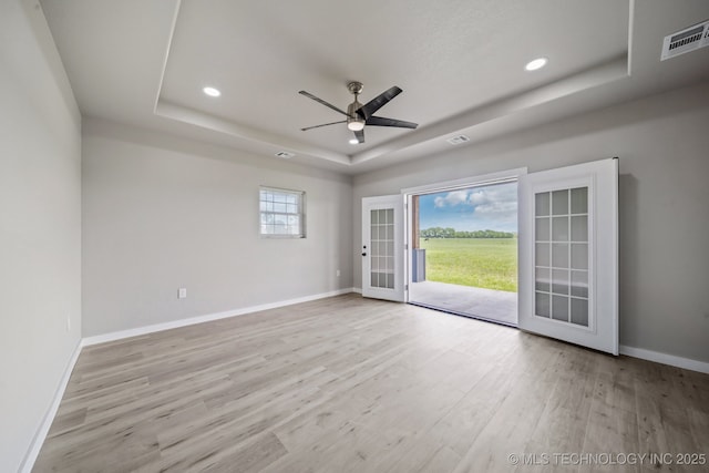 empty room featuring baseboards, ceiling fan, wood finished floors, and a raised ceiling