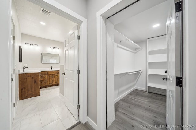 walk in closet featuring visible vents, a sink, and light wood-style floors