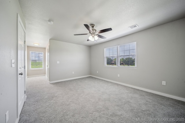 carpeted spare room with baseboards, a ceiling fan, and visible vents