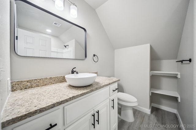 bathroom with vanity, toilet, baseboards, wood finished floors, and lofted ceiling